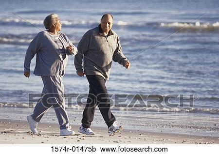 Stock Image - Senior couple walking at the beach. Fotosearch
