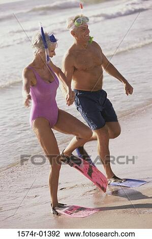 Stock Image - Senior couple wearing snorkeling gear on the beach. Fotosearch