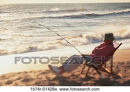 Senior man sitting on a beach chair with a fishing rod View Large Photo Image Stock Image - Senior man sitting on a beach chair with a fishing rod. Fotosearch