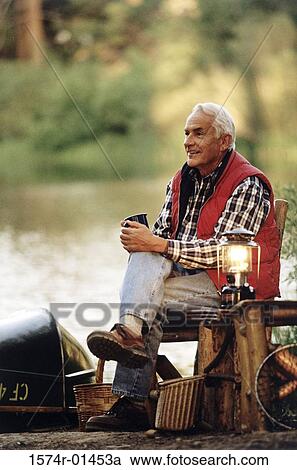 Stock Image - Senior man sitting outdoors on a chair. Fotosearch