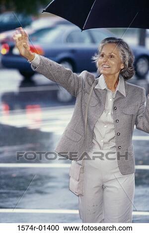 Senior woman standing outdoors with an umbrella View Large Photo Image Stock Image - Senior woman standing outdoors with an umbrella. Fotosearch