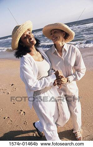Two women walking on the beach holding hands View Large Photo Image Stock Image - Two women walking on the beach holding hands. Fotosearch
