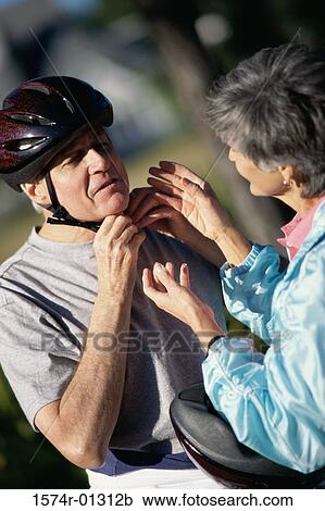 Woman helping a man put on a cycling helmet View Large Photo Image Stock Image - Woman helping a man put on a cycling helmet. Fotosearch