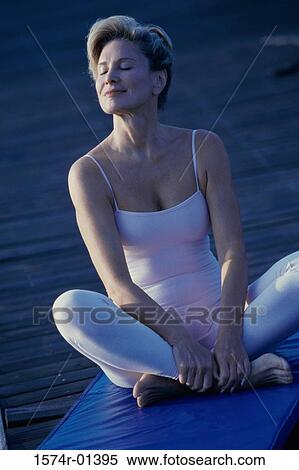 Stock Photography - Woman sitting on the floor with her eyes closed. Fotosearch