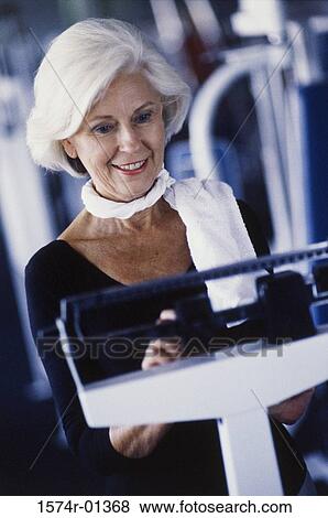 Stock Photo - Woman standing on a weight scale. Fotosearch
