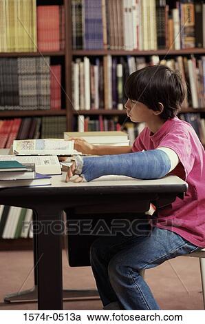 Stock Image - Boy sitting in a library and studying. Fotosearch