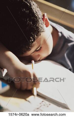 Stock Image - Boy sleeping on a desk holding a pencil. Fotosearch