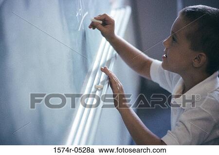 Stock Image - Boy writing on a chalkboard. Fotosearch