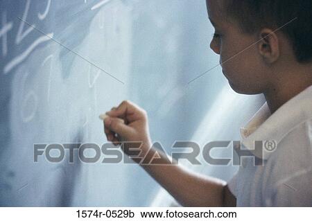 Stock Image - Boy writing on a chalkboard. Fotosearch