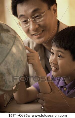 Stock Image - Father and son looking at a globe. Fotosearch