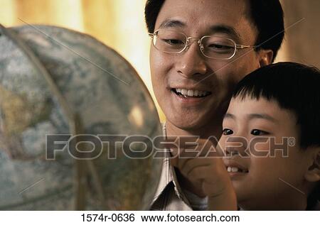 Father and son looking at a globe View Large Photo Image Stock Photograph - Father and son looking at a globe. Fotosearch