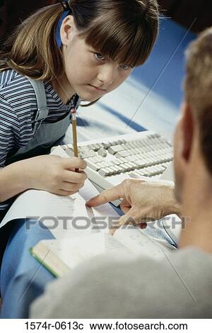 Stock Image - Father helping his daughter with homework. Fotosearch