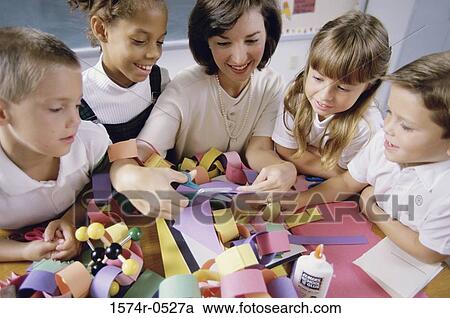 Stock Image - Female teacher teaching her students arts and crafts. Fotosearch