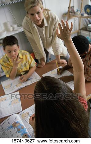 Stock Photo - High angle view of a girl raising her hand in class. Fotosearch