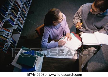 Stock Image - High angle view of a man and a teenage girl studying together. Fotosearch