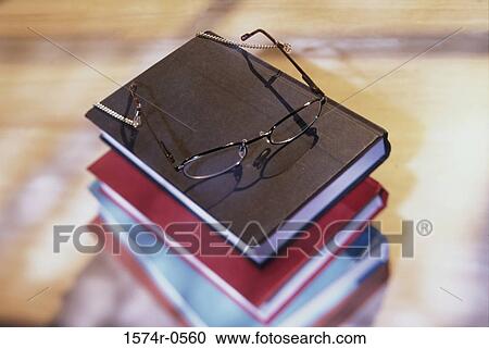 High angle view of stack of books with eyeglasses resting on top View Large Photo Image Stock Image - High angle view of stack of books with eyeglasses resting on top. Fotosearch