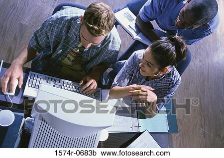 Stock Image - High angle view of two young men and a young woman studying together. Fotosearch