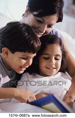 Stock Image - Mother and her two children reading a book. Fotosearch