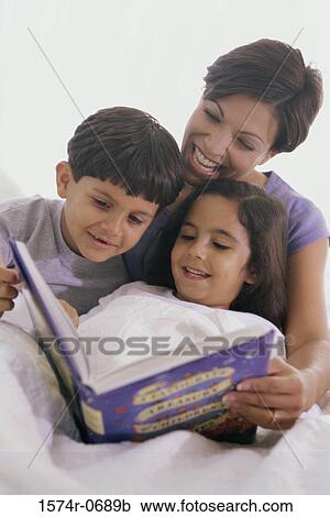 Stock Image - Mother and her two children reading a book. Fotosearch