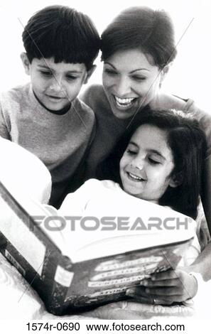 Stock Image - Mother and her two children reading a book. Fotosearch