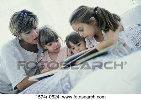 Picture - Mother sitting on a bed with her children. Fotosearch