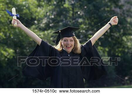 Stock Image - Portrait of a young woman wearing a graduation outfit holding a diploma. Fotosearch