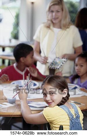 Portrait of children sitting at a table with a woman standing beside them View Large Photo Image Stock Image - Portrait of children sitting at a table with a woman standing beside them. Fotosearch