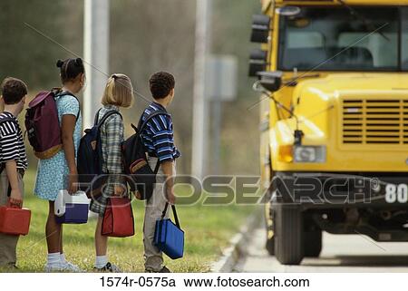 Stock Image - School children standing in line outside the school bus. Fotosearch