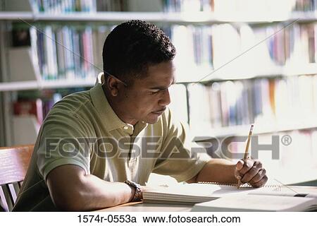 Stock Image - Side profile of a man writing in a notebook with a pencil. Fotosearch