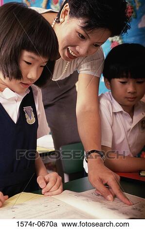 Stock Image - Teacher helping students in class. Fotosearch