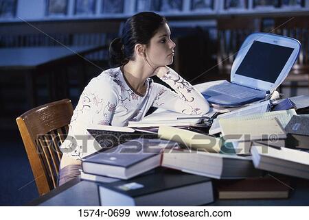 Stock Photo - Teenage girl sitting at table with books and a laptop. Fotosearch