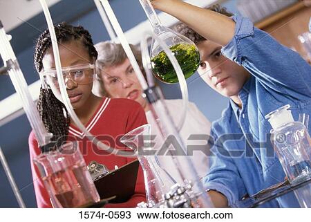 Stock Image - Teenagers conducting an experiment in a chemistry laboratory. Fotosearch