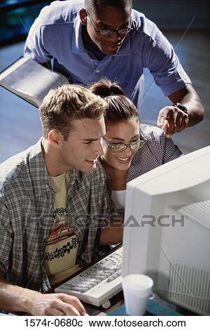 Stock Image - Two young men and a young woman studying together. Fotosearch