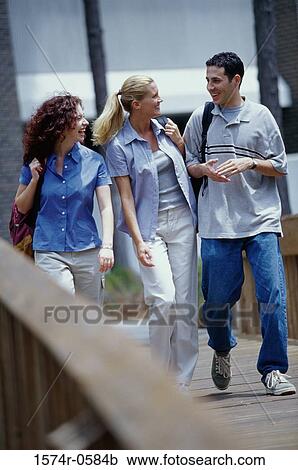 Two young women and a young man walking together View Large Photo Image Stock Image - Two young women and a young man walking together. Fotosearch
