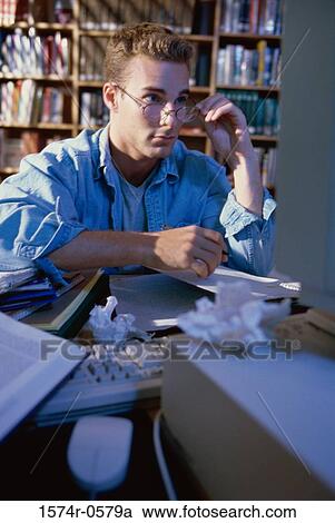 Stock Image - Young man sitting in front of a computer studying. Fotosearch