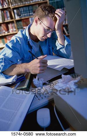 Stock Image - Young man sitting in front of a computer studying. Fotosearch