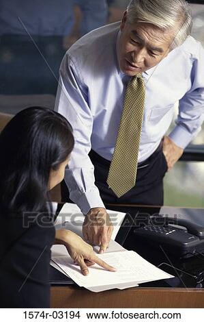 Businessman and a businesswoman pointing to a document View Large Photo Image Picture - Businessman and a businesswoman pointing to a document. Fotosearch