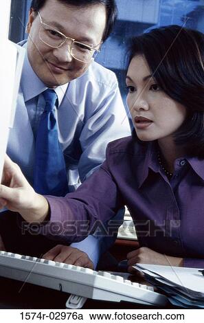Businessman and a businesswoman sitting in front of a computer View Large Photo Image Stock Image - Businessman and a businesswoman sitting in front of a computer. Fotosearch