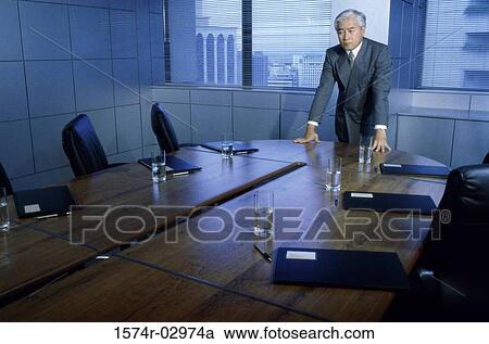 Businessman leaning on a conference table View Large Photo Image Stock Image - Businessman leaning on a conference table. Fotosearch