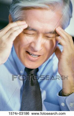 Stock Photograph - Close-up of a businessman holding his head. Fotosearch
