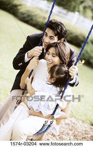 Close-up of parents playing with their daughter on a swing View Large Photo Image Picture - Close-up of parents playing with their daughter on a swing. Fotosearch