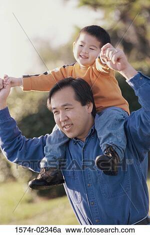 Stock Image - Father carrying his son on his shoulders. Fotosearch