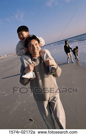 Father carrying his son on his shoulders walking on the beach View Large Photo Image Stock Image - Father carrying his son on his shoulders walking on the beach. Fotosearch