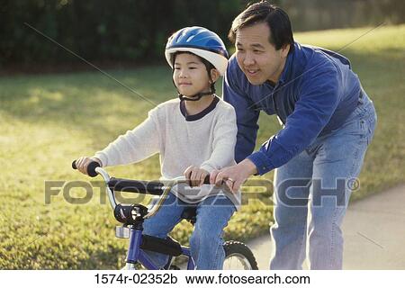 Father helping his son ride a bicycle View Large Photo Image Stock Image - Father helping his son ride a bicycle. Fotosearch