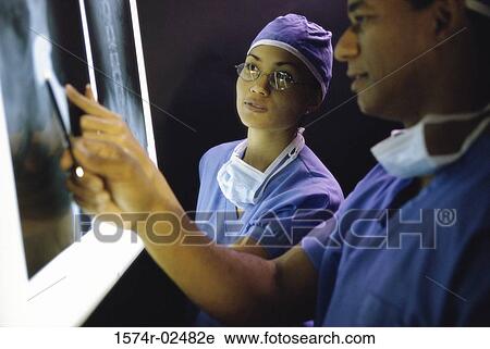 Stock Image - Male doctor and a female doctor examining an x-ray report. Fotosearch