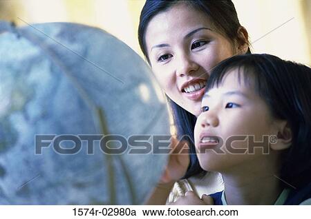 Stock Image - Mother and her daughter looking at a globe. Fotosearch