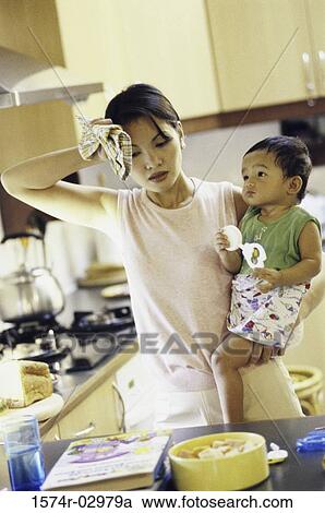 Stock Image - Mother carrying her son in the kitchen. Fotosearch