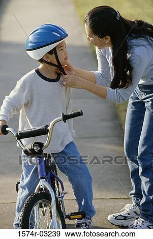 Mother fastening her son's helmet View Large Photo Image Stock Photo - Mother fastening her son's helmet. Fotosearch