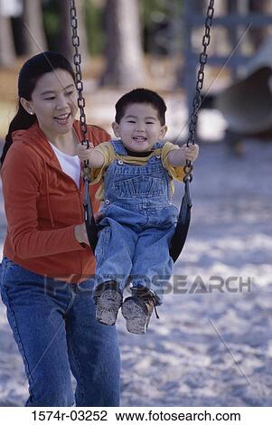 Mother pushing her son on a swing View Large Photo Image Stock Image - Mother pushing her son on a swing. Fotosearch