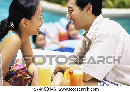 Stock Photograph - Parents looking at each other with their children in a swimming pool. Fotosearch